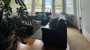 Une pièce avec un plafond en bois, de grandes fenêtres, un canapé et une plante en pot.