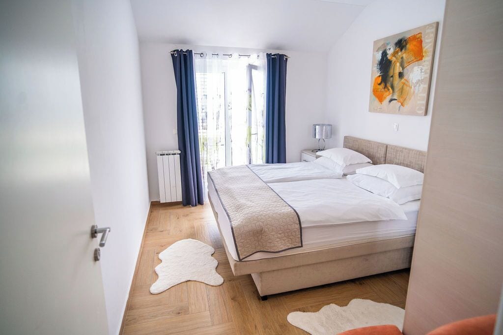 A bedroom with a bed, a nightstand, a lamp, and a painting on the wall.