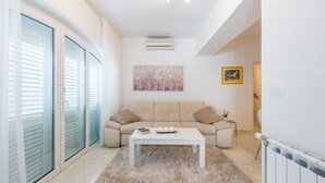 Een moderne woonkamer met een beige bank, een witte salontafel en een zacht vloerkleed.
