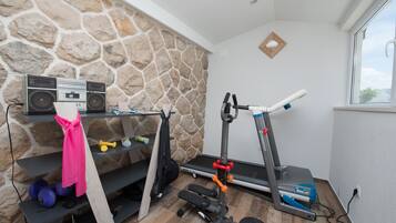 Ein Heimfitnessraum mit Steinwand, Laufband, Kurzhanteln und Radio.