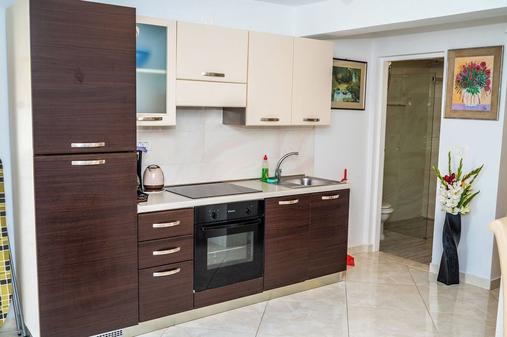 A modern kitchen with dark wood cabinets, a built-in oven, and a stainless steel sink.