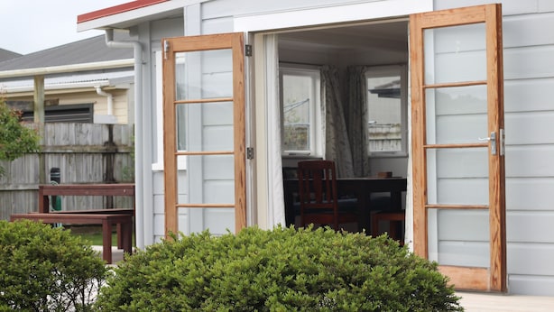 Una casa residencial con un patio cubierto al que se accede por un cerramiento de vidrio corredero.