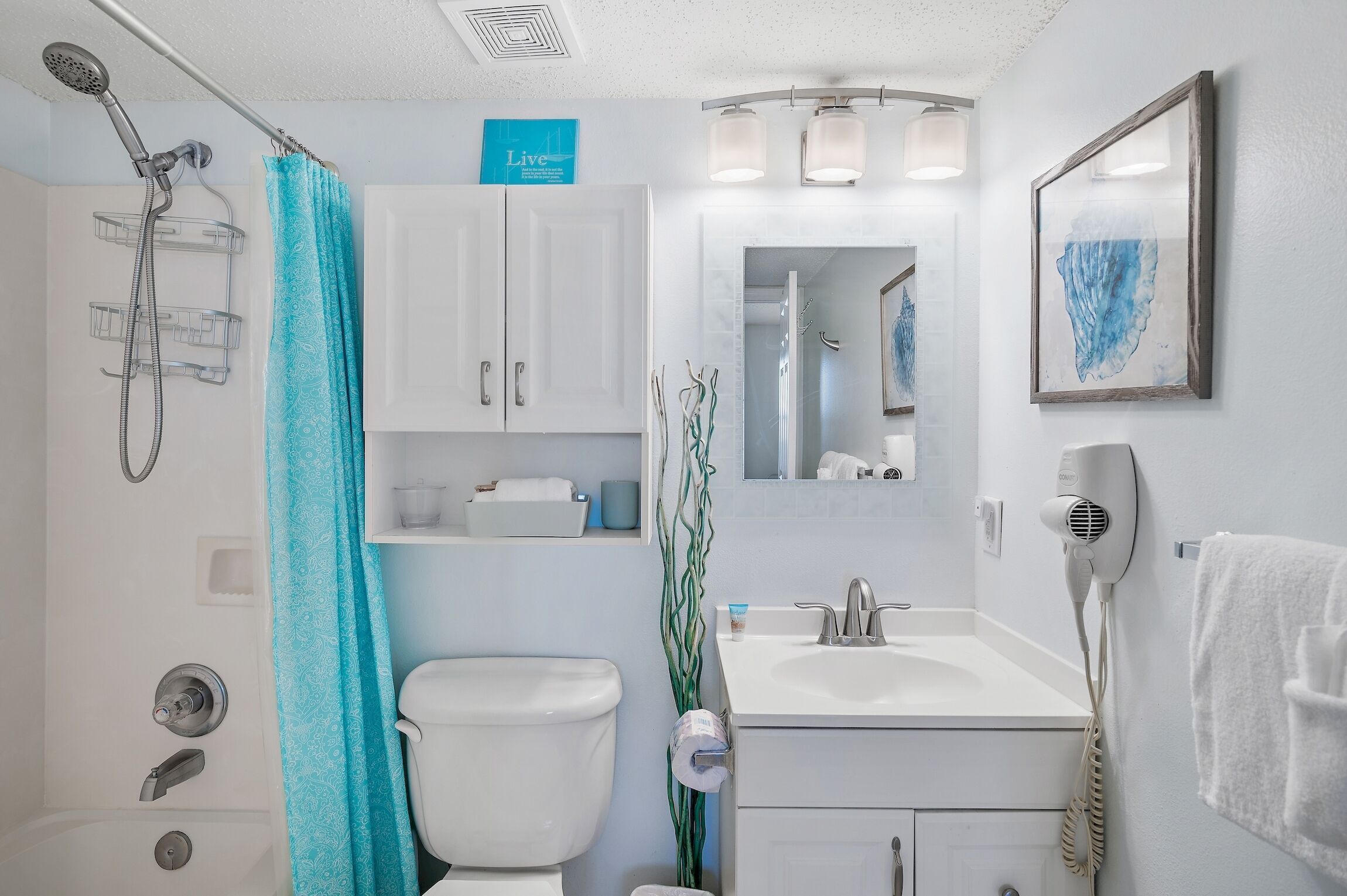 A bathroom with a shower, toilet, sink, and a hairdryer.