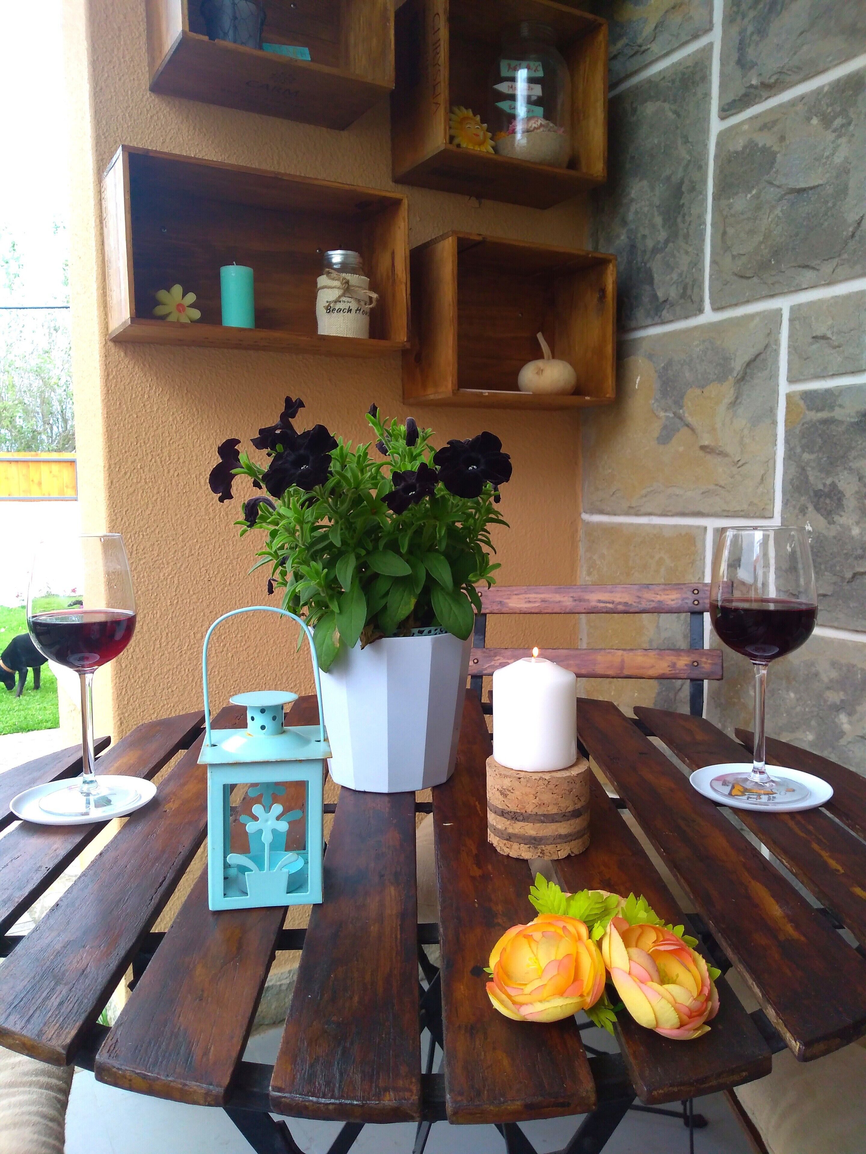 A wooden table with two wine glasses, a candle, a potted plant, and a lantern.