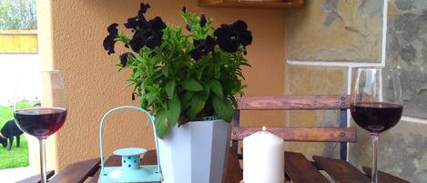 A wooden table with two wine glasses, a candle, a potted plant, and a lantern.