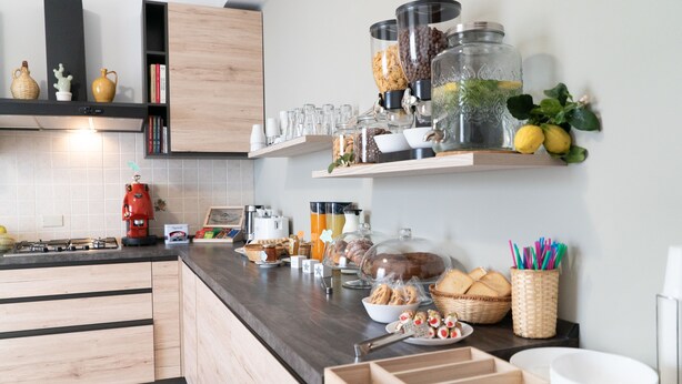 Una cocina moderna con armarios de madera, una encimera oscura y diversos alimentos y utensilios de cocina.