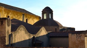 Un edificio con una cupola e un campanile, caratterizzato da una facciata consunta e un tetto in tegole.