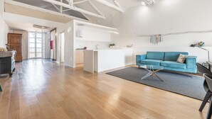 A spacious living area with a blue sofa, a coffee table, and a kitchen in the background.