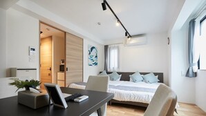 A modern hotel room with a bed, a desk with a laptop, a small plant, and a window with curtains. - A1 Maison Phillippe Shitaya 101 (Tokyo)
