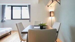 A modern room with a bed, a dining table with chairs, a potted plant, and a floor lamp. - A1 Maison Phillippe Shitaya 101 (Tokyo)