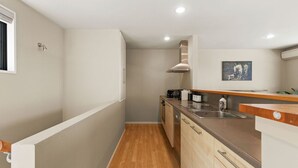 Une cuisine compacte avec un plancher en bois, un four encastré, un four à micro-ondes et un évier.