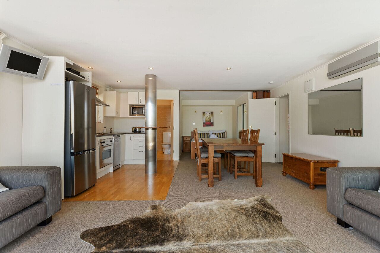 A modern kitchen with a built-in oven, a stainless steel refrigerator, and a dining area with a wooden table and chairs.