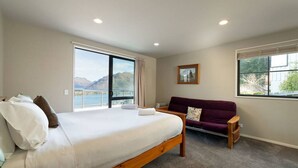 Une chambre avec un grand lit, un canapé et une fenêtre donnant sur la montagne.