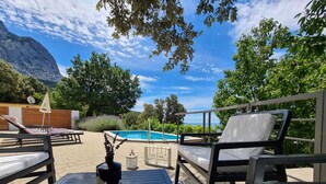 A poolside area with lounge chairs, a table, and a bottle.