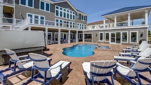 A multi-story building with a pool area featuring lounge chairs and a covered seating area.