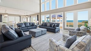 A spacious living room with multiple sofas and a view of the beach.