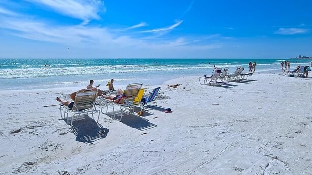A beach with sun loungers and people relaxing. - Spacious Condo in a Great Location! Private Beach, 2 Pools, 2 Jaccuzi, Fishing Deck & More! (Siesta Key)