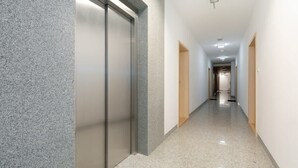 A hallway with a sliding door, a light fixture, and a door at the end.