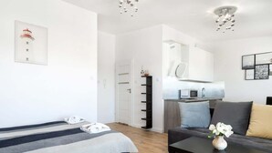 A modern bedroom with a bed, a sofa, and a dining area.