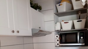 A kitchen with white cabinets, a stainless steel sink, a microwave, a coffee maker, and a dishwasher. - Studio-cabin in RDJ, with your feet in the water! (Antheor)