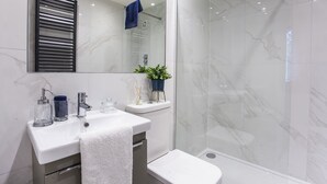 Een moderne badkamer met een wit wastafel, toilet en douchecabine.