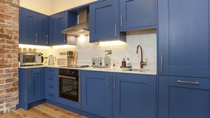 Een moderne keuken met blauwe kastjes, roestvrijstalen apparatuur en een houten vloer.