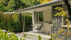Een huis met een stenen gevel, een overdekte veranda met twee stoelen, en een raam.