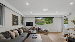 Een moderne woonkamer met een bank, een salontafel, een televisie en een eethoek met stoelen.