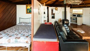 Habitació senzilla amb llit, sofà, petita cuina i taula de menjador.