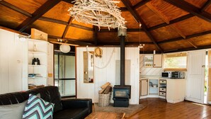 Interior acollidor d'una cabana amb zona de estar, cuina i una llar de llenya.