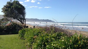 Una platja amb onades oceàniques, un arbre i vegetació verda.