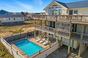 Une maison à deux étages avec une piscine et un espace extérieur aménagé pour s’asseoir.