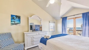 A bedroom with a bed, a dresser, a chair, a ceiling fan, a painting, and a window with curtains. - Sea Spirit | 717 ft from the beach | Dog Friendly, Private Pool, Hot Tub | Kitty Hawk (Kitty Hawk)