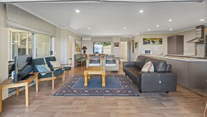 A spacious living area with a sofa, chairs, a coffee table, and a kitchen area with a microwave. - Lakeside Vistas Magic - Rainbow Point Home (Rainbow Point)