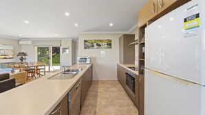 A modern kitchen with a central island, built-in oven, and a refrigerator. - Lakeside Vistas Magic - Rainbow Point Home (Rainbow Point)