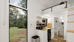 Une cuisine compacte avec vue sur l’extérieur, une petite poubelle et un four à micro-ondes.