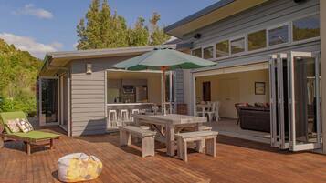 Relax in the serene outdoor patio, complete with a dining table and comfortable seating under a spacious umbrella.