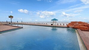 Ein Schwimmbad mit Holzterrasse, einem Pavillon und einer Felsformation.