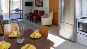 Een moderne keuken met een roestvrijstalen koelkast, een eettafel met gele borden en bekers, en een grote vaas.