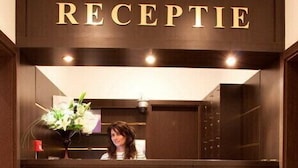 A reception area with a wooden reception desk, a receptionist, and a logo on the desk. - Pensiunea SIERA (Constanta)