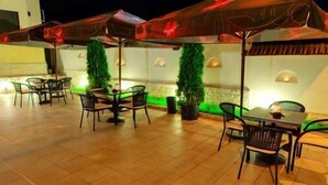 An outdoor patio with multiple tables and chairs, some under umbrellas. - Pensiunea SIERA (Constanta)