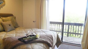 A bedroom with a bed, a tray with wine glasses and flowers, a door, and a balcony with a railing. - Extra Clean Next Beech Mountain Ski Resort (Beech Mountain)