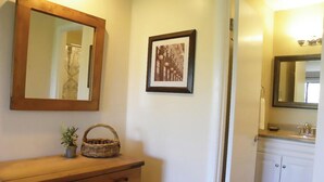 A wooden dresser with a basket and a small plant, a framed picture on the wall, and a bathroom with a sink and mirror. - Extra Clean Next Beech Mountain Ski Resort (Beech Mountain)