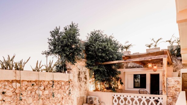 Une terrasse extérieure moderne, avec des murs en pierre, des plantes en pot et du mobilier d’extérieur.