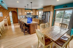 Una cocina amplia con armarios de madera, una isla grande y un comedor con sillas.