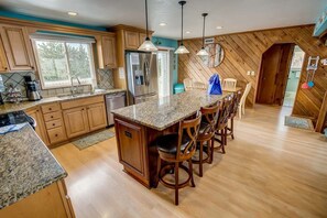 Una cocina con armarios de madera, encimeras de granito y una isla central con taburetes de bar.