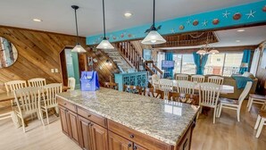 A spacious kitchen with a granite island, wooden cabinets, and pendant lighting. - Summer Slope | 130 ft from the beach | Private Pool (Virginia Beach)