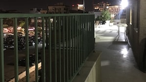 A balcony with a metal railing, a table, and chairs.