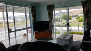 Een woonkamer met een televisie, een bank, een salontafel en een schuifdeur naar een terras.