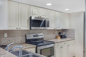 A kitchen with white cabinetry, a stainless steel microwave, a gas stove, and a built-in oven.
